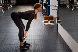 A woman performing barbell RDL with proper hip hinge mechanics